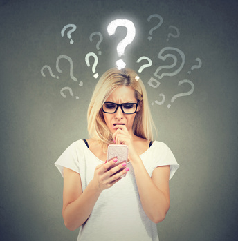 Misunderstanding and distant call. Upset confused woman talking or texting on mobile phone has many questions isolated on gray background.